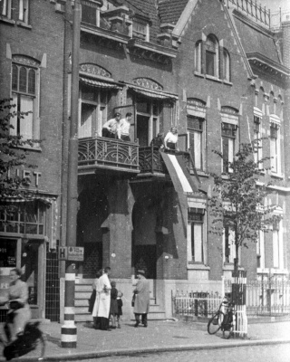 Een vlag wordt aan een balkon gehangen in Rotterdam (4 september 1944)