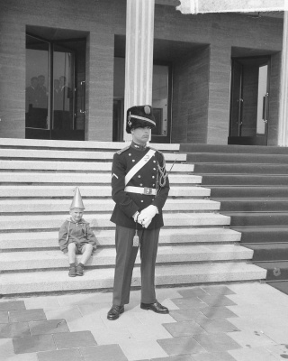 Koningin Juliana opent het nieuwe stadhuis te Vlissingen. Een jongetje met feestmuts zit op de trappen van het bordes van het stadhuis. Voor hem staat een marechaussee, 1965. Foto Jac. de Nijs, Nationaal Archief / Collectie Anefo