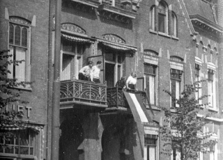 Een vlag wordt aan een balkon gehangen in Rotterdam (4 september 1944)