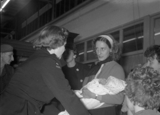 Aankomst KLM-vliegtuig "Maastricht" op Schiphol met Indonesische evacués uit Singapore. Achter de balie mevr. L. van Overeem van het Rode Kruis. Foto Eric Koch / Anefo